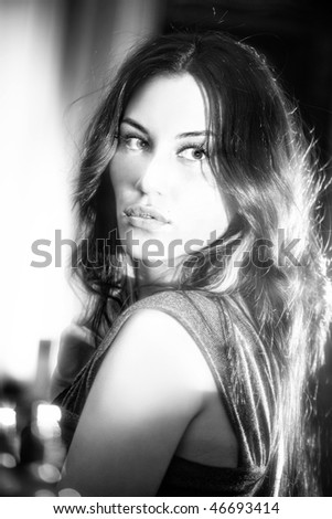 BW portrait of attractive brunette sexy girl with beautiful hairstyle. Girl reflect in mirror with dust making beams and soft focus effect on hair.