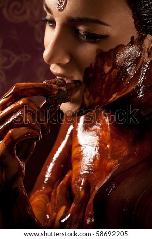 Woman covered in melted chocolate tastes chocolate bar and enjoy