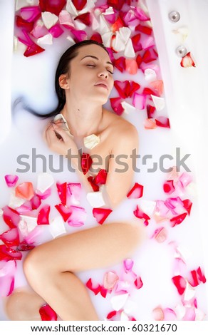 stock photo Attractive naked girl enjoys a bath with milk and rose petals