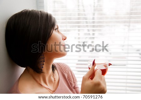 Brunette woman look at window and relaxing with cup of hot tea