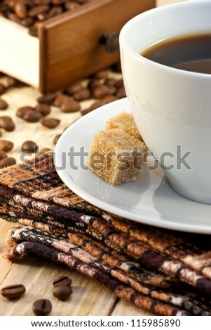 cup of coffee, sugar cane and coffee beans on a wooden board