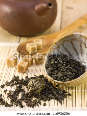 Asian tea, sugar cane, and a ceramic teapot on bamboo napkin