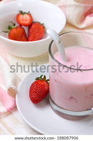 strawberry yogurt in glass, fresh strawberries in a bowl (focus on strawberry)
