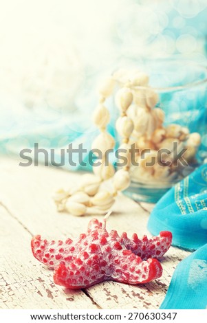 beach house decor, setting summer vacation : Candle in the form of starfish, shells, pareo on the wooden background  (Toning, bokeh)