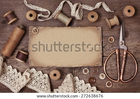 old spools of thread, scissors, lace, buttons on the old wooden background (toning)