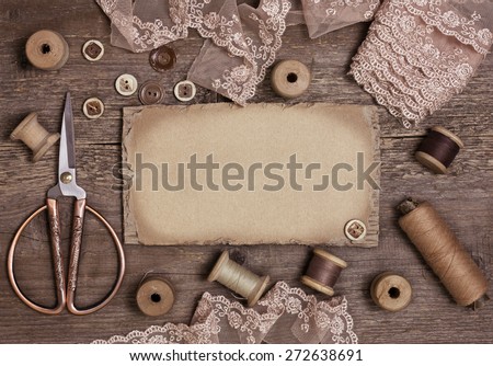 old spools of thread, scissors, lace, buttons on the old wooden background (toning)