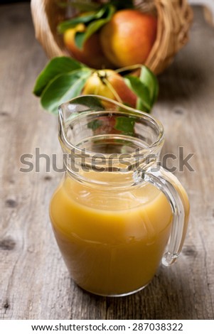 pear juice in a jug, a basket of pears on a wooden background