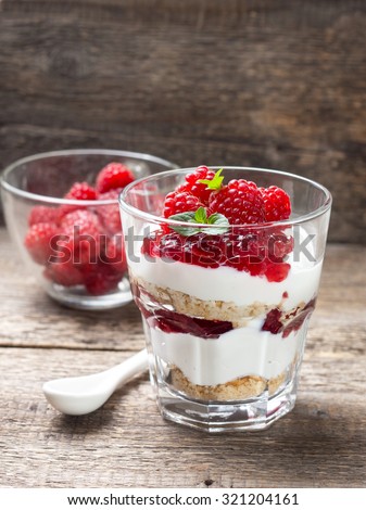 cheesecake with raspberries, mint in glass on old wooden background (Focus on raspberries)