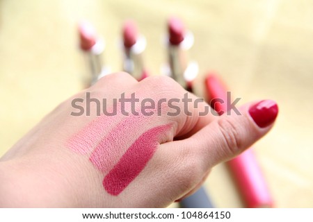 A female is trying three different shades of lipstick on her hand to see which matches the skin colour when shopping for makeup