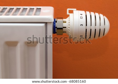 Radiator heater with thermostat isolated on orange background