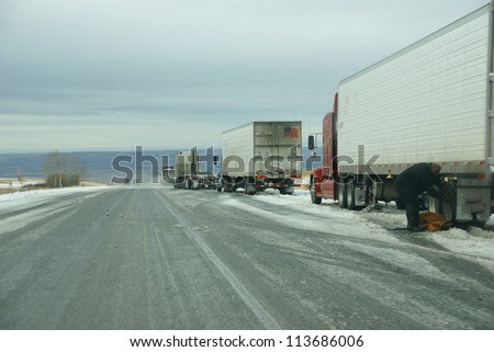 Trucks stop to remove chains after passing through a winter storm in Eastern Oregon