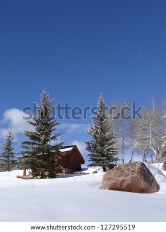 Snow bound cabin in winter landscape with large boulder in Vail Valley, Colorado