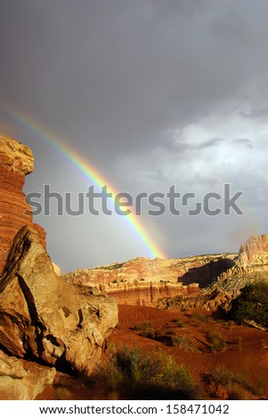 Rainbow and brief dramatic sunshine before sunset,  on cliffs in Capitol Reef National Park, Utah