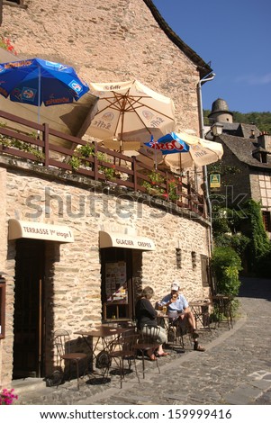 CONQUES, FRANCE - SEP 23 - A couple enjoys a leisurely lunch outside a small restaurant on Sep 23, 2011 in Conques, France