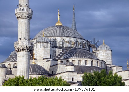 Sultan Ahmet Camii ( Blue Mosque ) glows in early evening light against dark clouds in the background  in Istanbul, Turkey
