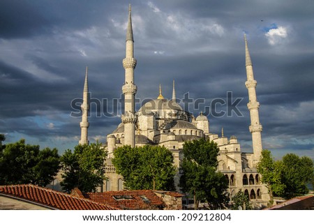 Sultan Ahmet Camii ( Blue Mosque ) glows in early evening light against dark clouds in the background  in Istanbul, Turkey