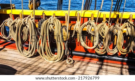 Coiled rope lines stored on belaying pins  on a wooden tall ship