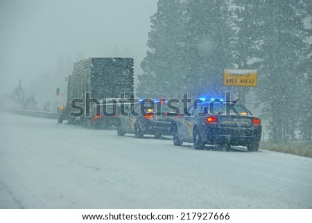 Police cars stop to assist  a large truck during a winter storm  in Eastern Oregon