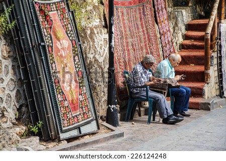 ANTALYA, TURKEY - JUN 2, 2014 - Two old men checking their cellphones outside their carpet shop,  Antalya,  Turkey