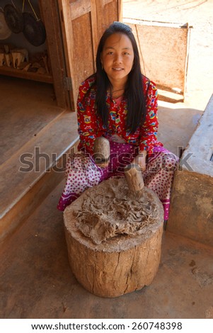 INLE LAKE, MYANMAR - FEB 28, 2015 - Young woman hammers mulberry pulp to make paper, near Inle Lake Myanmar (Burma)