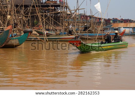 KOMPONG KLEANG, CAMBODIA - FEB 12, 2015 - Power boat travels along the waterway of Kompong Kleang floating fishing village,  Cambodia