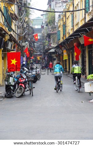 HANOI, VIETNAM - FEB 1, 2015 - Bicycles on narrow street, with red Vietnamese flag,  Hanoi,  Vietnam
