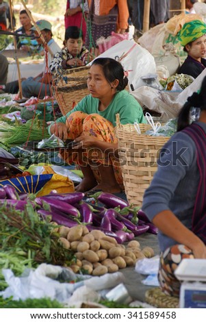 INLE LAKE, MYANMAR - MAR 1, 2015 - Young woman selling fresh vegetables at the weekly market on  Inle Lake,  Myanmar (Burma)