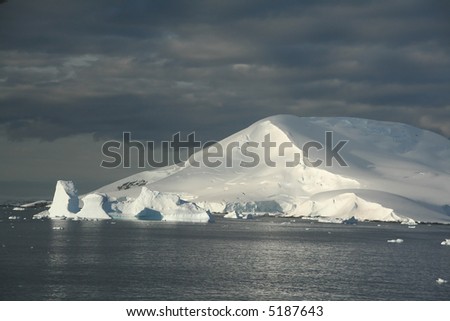 Icebergs and snow covered mountain, with blue sky & Calm seas.		Petermann Island,	Antarctica