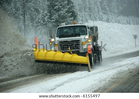 Snowplow clearing road in snowstorm,		Rocky Mountains,	Idaho