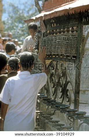 KATHMANDU NEPAL - CIRCA OCTOBER 1979 : Worshipers spin the prayer wheels in the Buddhist temple on Sywambunath circa October 1979 in Kathmandu, Nepal.
