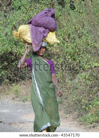 ORISSA, INDIA - NOV 11: A woman carries goods on her head to a weekly market on Nov 11, 2009 in Orissa, India.