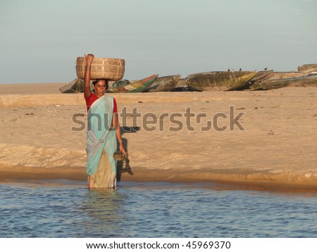 ORISSA, INDIA - NOV 14 - Orissa woman crosses tidal waters while carrying goods on her head   on Nov 14, 2009, in Puri, India.