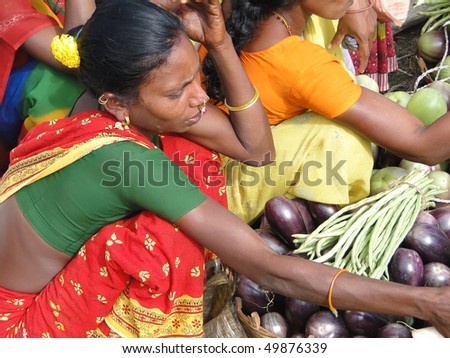 ORISSA, INDIA - NOV 11 : Woman in red sari sells eggplants at Chatikona market on November 11, 2009,  in Orissa, India