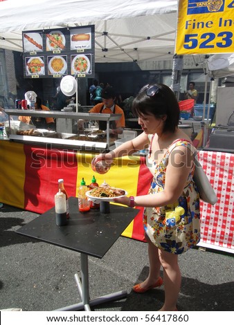 SEATTLE - MAY 15 -  Young Asian woman samples the food   at the U District Street Fair on May 15, 2010, in Seattle