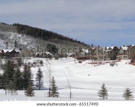 Cross country skier moves across snowy meadows under large houses Colorado