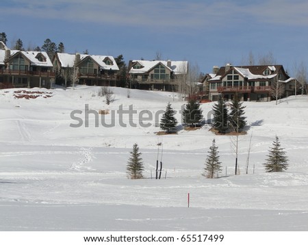 Cross country skier moves across snowy meadows under large houses Colorado