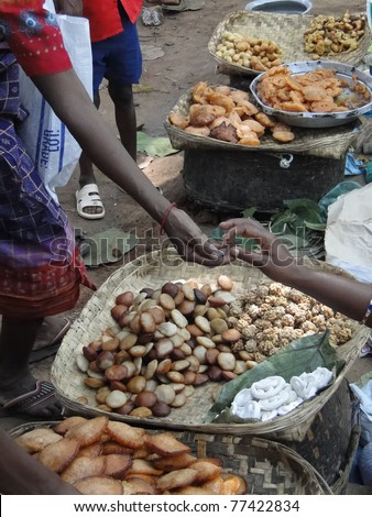 Woman buys fried snacks at a weekly market   in Orissa,  India