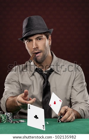 Poker player wearing hat and smoking a cigar, on a red background, throwing two ace cards.