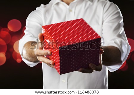 A Man holding a gift box in a gesture of giving.