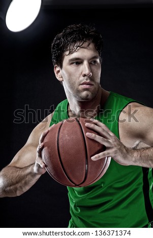Basketball player with a ball in his hands and a green uniform. photography studio.