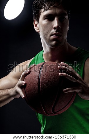 Basketball player with a ball in his hands and a green uniform. photography studio.