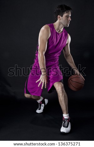 Basketball player with a ball in his hands and a pink uniform. photography studio.