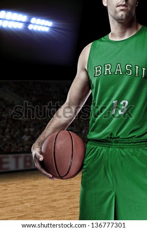 Brazilian Basketball player with a ball in his hands and a green uniform. photography studio.