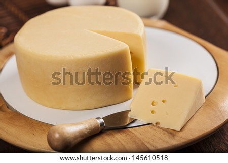 Slice of cheese with a knife on a wooden table.