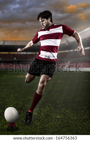Rugby player in a red uniform kicking a ball on the Stadium