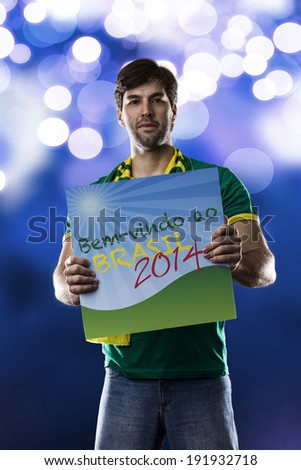 Brazilian Fan holding a welcome to Brazil sign, (Bem-vindo ao Brasil), written in Portuguese., on a blue background.