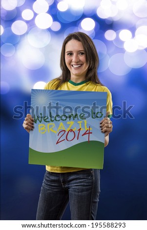 Female Brazilian Fan holding a welcome to Brazil sign, on a blue lights background.