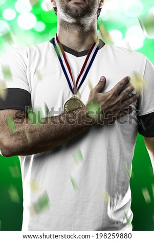 German soccer player, listening to the national anthem with his hand on his chest. On a green lights background.
