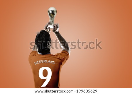 Dutchman soccer player, celebrating the championship with a trophy in his hand. On a orange background.