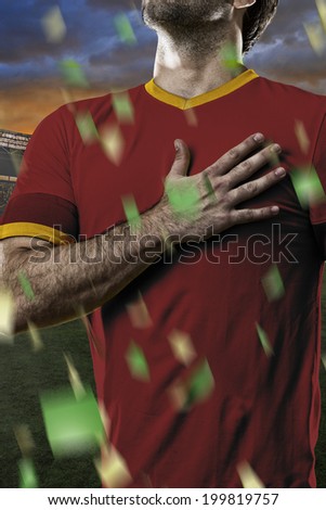 Spanish soccer player, listening to the national anthem with his hand on his chest. On a stadium.